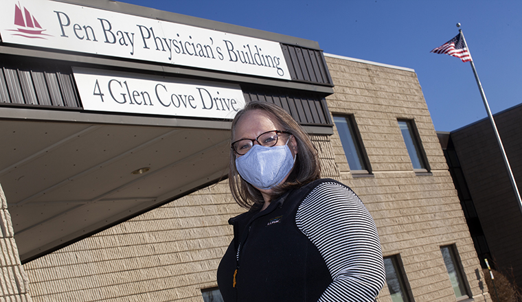 a woman wearing a mask standing outside Pen Bay Physician's Building
