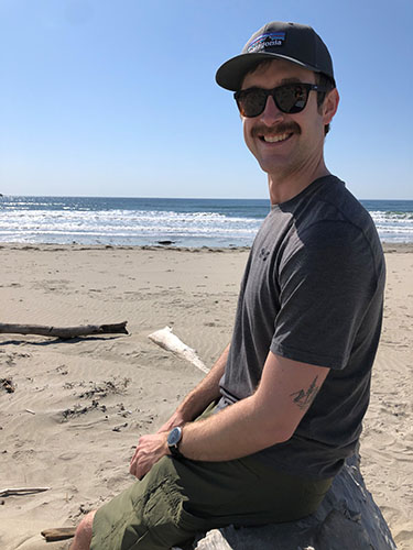 Smiling man in sunglasses and baseball hat at the beach