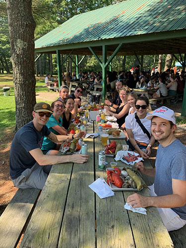 large group of people eating lunch together in a campground setting