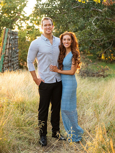 smiling young man and woman standing together in a pastoral country field