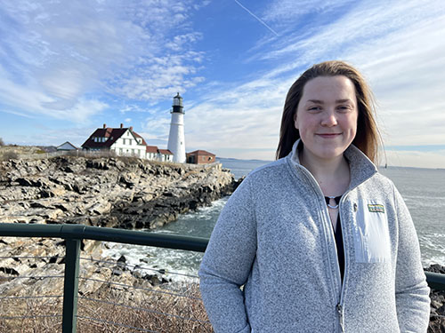 A young woman standing in front of the Portland Headlight lighthouse