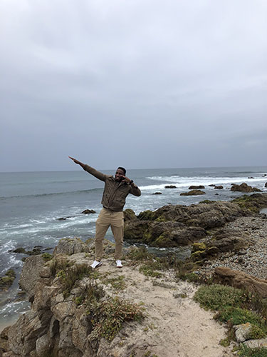 a man standing on rocks next to the ocean