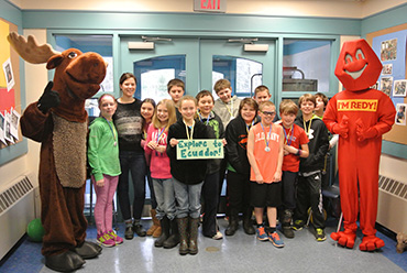 Group of adults and kids standing with two mascots
