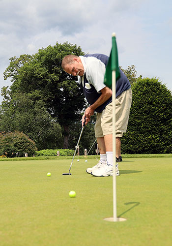 a man putting a golf ball towards the hole