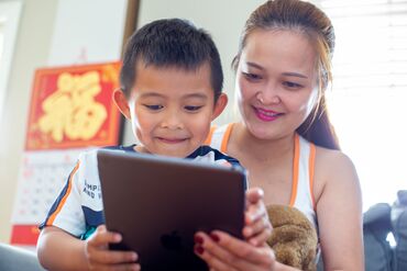 Lori Nguyen watches her 5 year old son, Billy Ha, play on an iPad