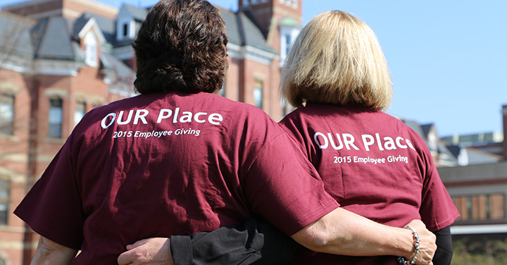 Back view of two people wearing maroon t-shirts that read "our place"